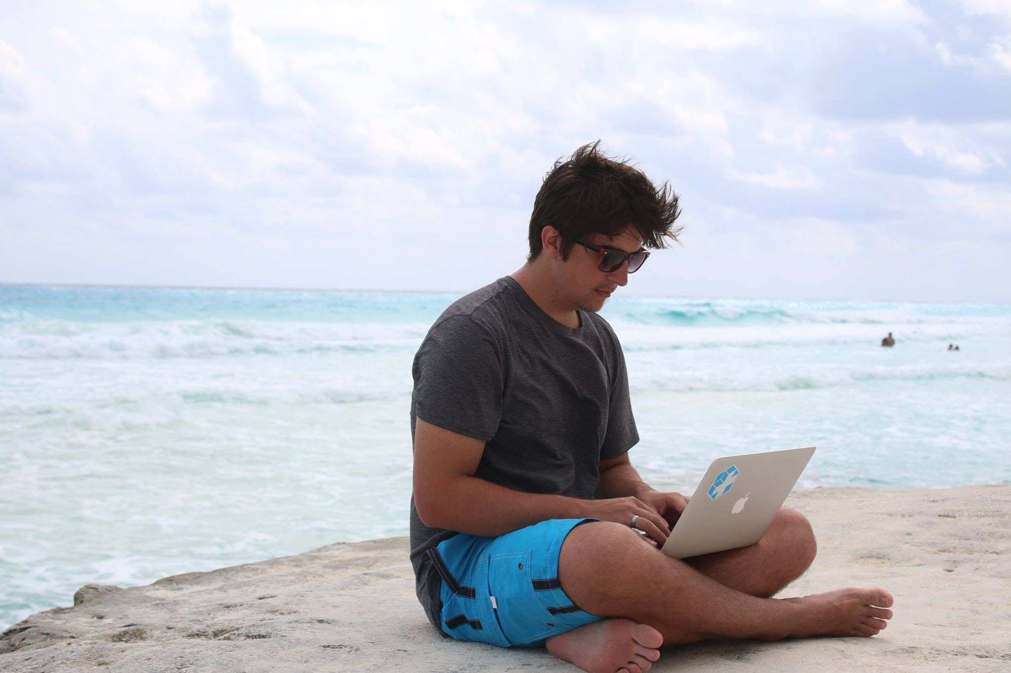 Alex using a laptop beside the ocean